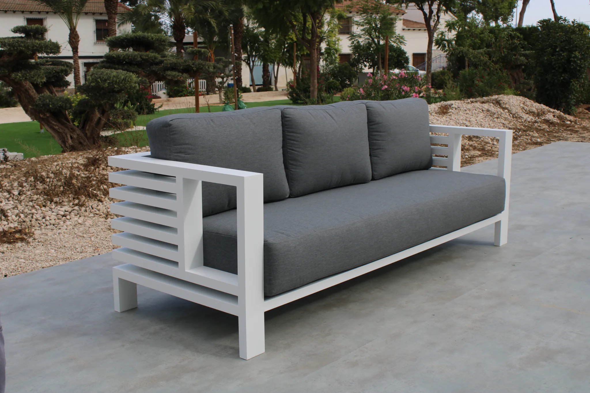 Sofá exterior de aluminio de 3 plazas y fabricado en aluminio de color blanco. Los cojines de jardín son de color gris.